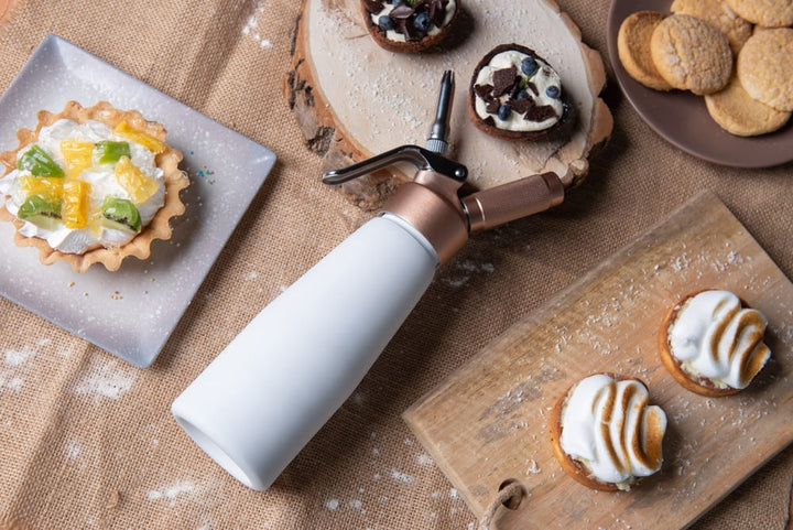 Person spraying whipped cream on coffee using a dispenser
