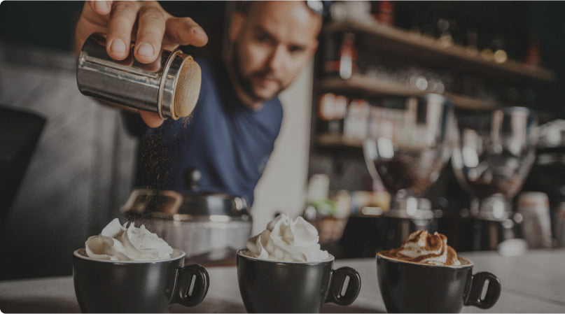 Spreading Cinnamon On A Coffee With Whipped Cream